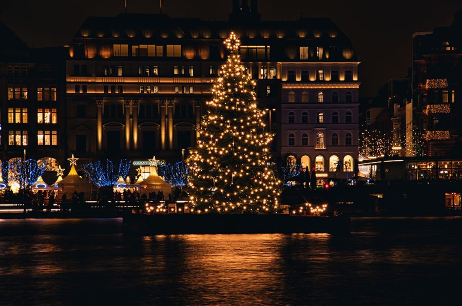 A lit Christmas tree reflected in water at night